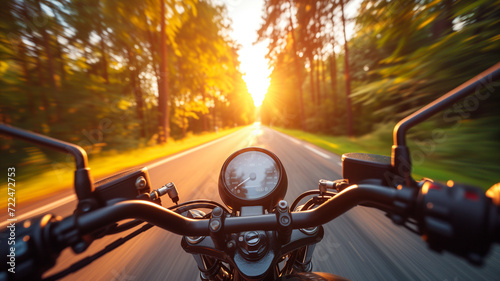 A motorcycle speeds on a road between trees at sunset, motorcyclist's point of view photo