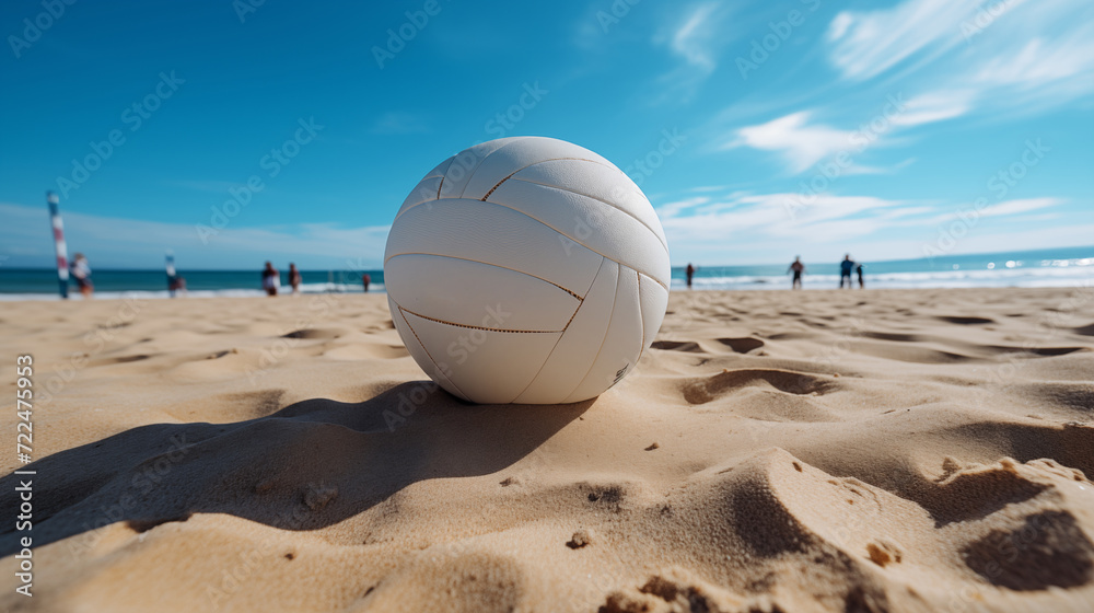 A white volleyball lies on a sandy beach
