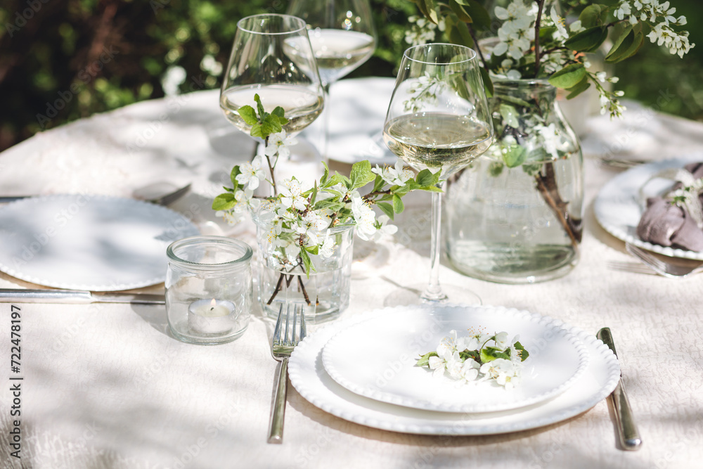 Rustic zero waste wedding decor with natural elements. Fresh spring blooming flowers, candles, linen napkins, wine glasses. Eco friendly decoration for the special holiday dinner. Romantic cozy place