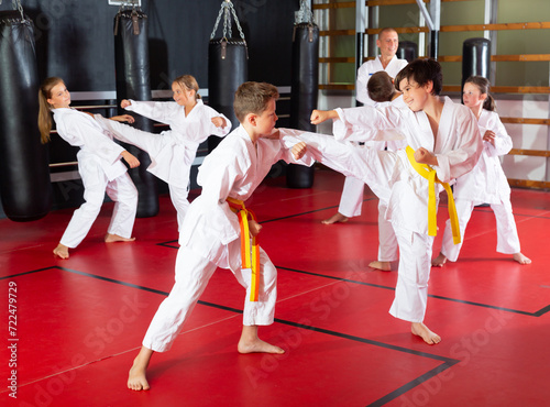 Adolescent boys and girls in kimono fighting with each other in gym.