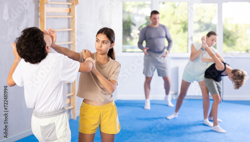 Boy and girl training self-defense techniques in group in studio