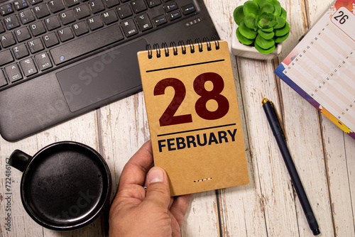 Cube shape calendar for February 28 on wooden surface with empty space for text. photo