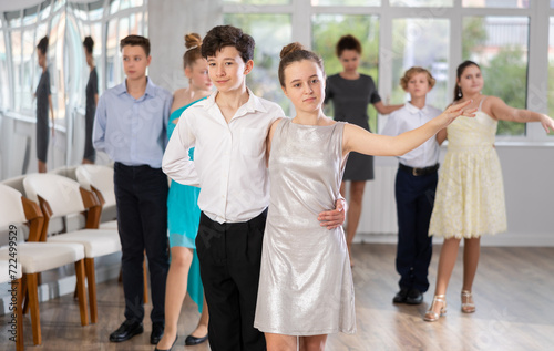 During rehearsal of reporting concert, adolescence boy and girl participants of dance workshop perform quickstep under guidance of female mentor