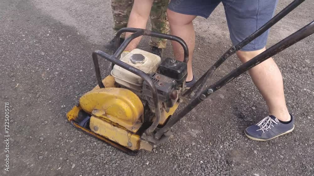Hands and legs of man turning off and stopping plate compactor near man Hands and legs of man turning off and stopping plate compactor near man