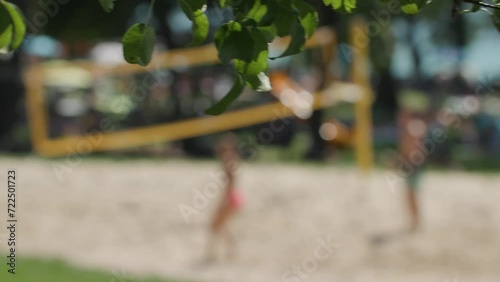 young people playing beach volleyball near lake in summer photo