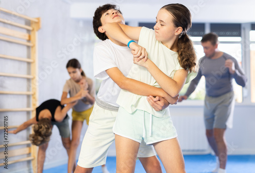Preteen children pairs learning strength self-defense in the gym