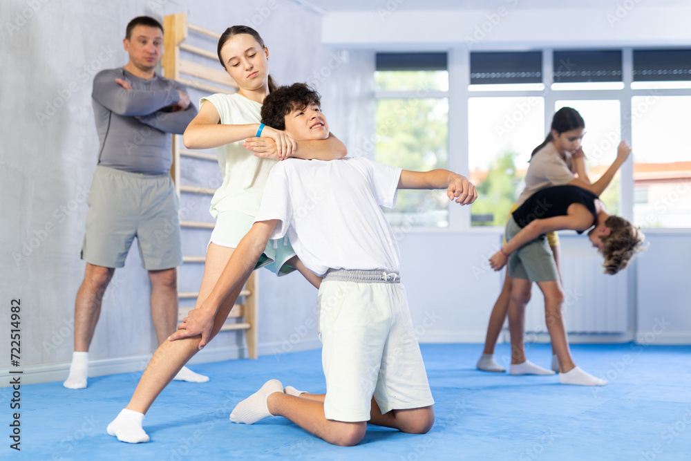 Fototapeta premium Boy and girl practicing self-defense techniques in group at gym