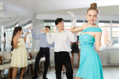 Teen boy paired with girl practices movements of twist dance and trains to perform movements during lesson in choreography studio.