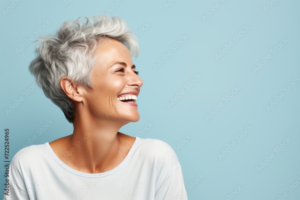 Portrait of a happy senior woman laughing against a blue background. Portrait of a happy senior woman laughing against a blue background.