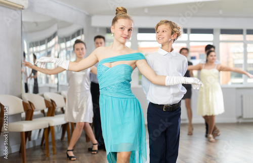 Fototapeta Naklejka Na Ścianę i Meble -  During rehearsal of reporting concert, adolescence boy and girl participants of dance workshop perform quickstep under guidance of female mentor