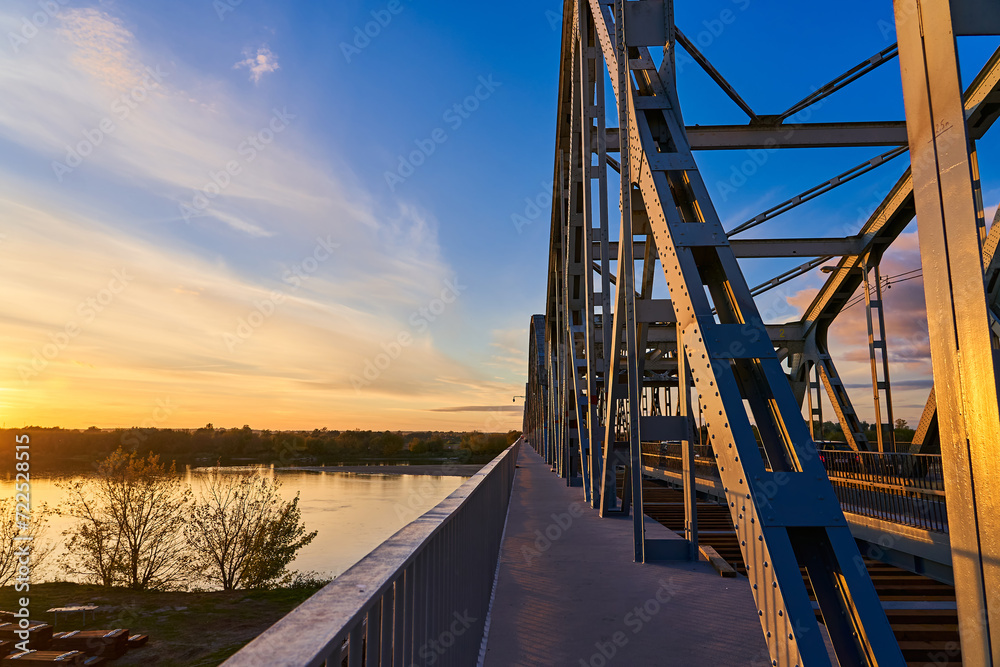 Railway bridge over the river on the background of sunset and blue sky