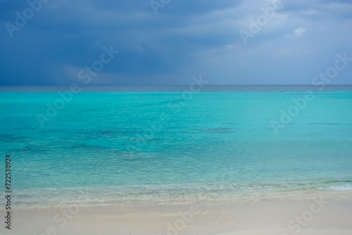 Purplish sky and rain in distance at Caribbean sea, beautiful turquoise water under dark blue clouds.