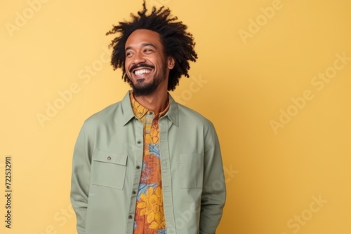 Portrait of a happy young african american man laughing over yellow background