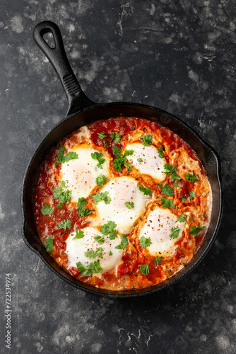 Healthy shakshuka with vegetables, herbs, tomatoes in iron cast pan