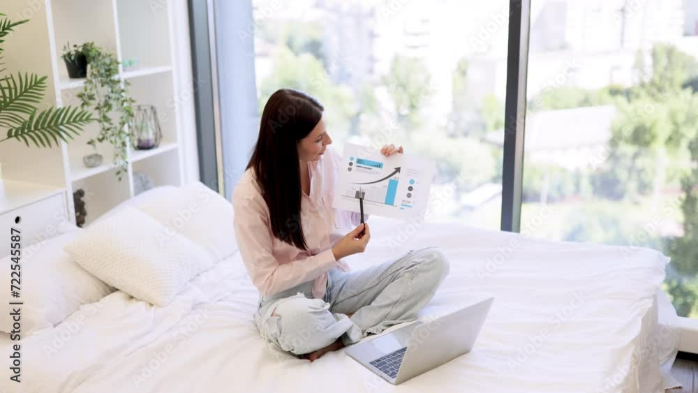 Portrait of young woman manager showing report with graphs and charts while working on modern laptop. Caucasian brunette working remotely enjoying online chatting with colleagues from home . Portrait of young woman manager showing report with graphs and charts while working on modern laptop. Caucasian brunette working remotely enjoying online chatting with colleagues from home .