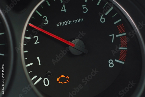 A close-up view of a car's tachometer with the check engine warning light illuminated, indicating a potential issue with the vehicle's performance or emissions system.