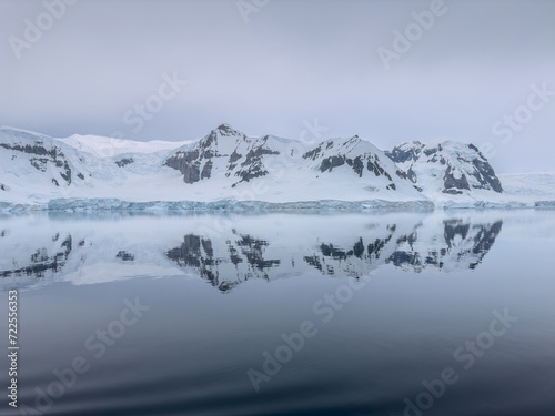 A huge high breakaway glacier in the southern ocean off the coast of Antarctica, the Antarctic Peninsula, the Southern Arctic Circle, azure water, cloudy weather