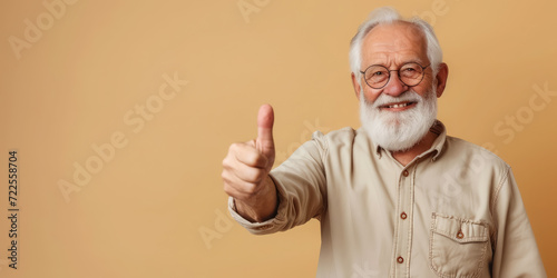 smiling elderly gray-haired man in glasses shows thumbs up on a colored background in the studio, pensioner, old age, grandfather, portrait of a mature person, beard, casual wear, gesture, happy photo