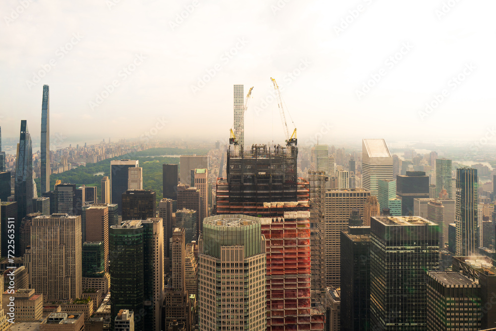 Fototapeta premium New York City, USA, a hazy polluted low mist engulfs the sky. Looking down on skyscrapers. New skyscraper is being built with Central Park in the background