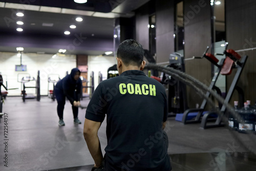 sports coach. Gym trainers seriously train their members to lift weights in gym classes.
