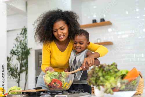 Portrait of enjoy happy love african american family mother and african little boy son child having fun help cooking food healthy eat together with fresh vegetable salad and ingredient in kitchen photo
