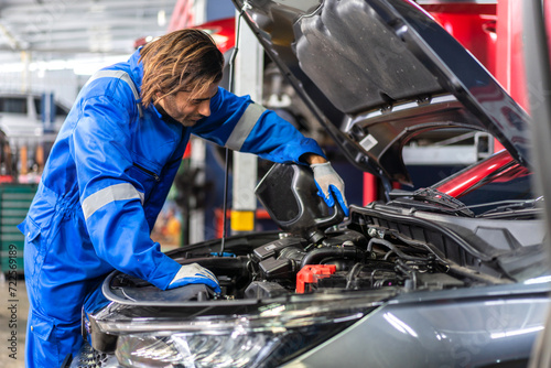 Car technician mechanic man in uniform work fixing vehicle car engine and maintenance repairing checking under the car hood in auto service. Automobile service garage