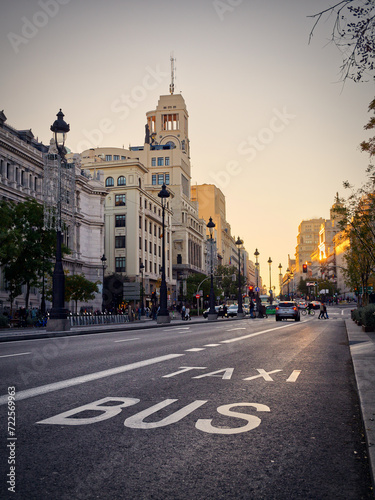 Madrid, Spain - November 19, 2023: Bus and Taxi empty lane in Gran VIa avenue under sunset colors