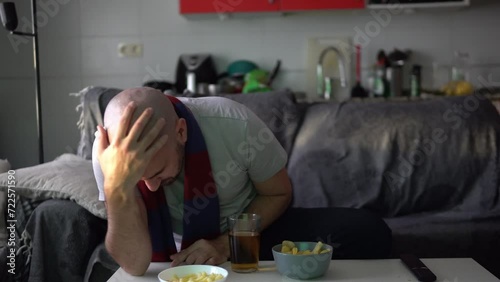 Defeated young man watching sports on the sofa celebrates a goal
