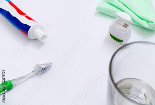 Salud bucodental. Artículos de higiene bucal, cepillo, hilo dental, crema o pasta de dientes, agua y paño verde. Limpieza dental. Superficie blanca y espacio para copiar.  photo