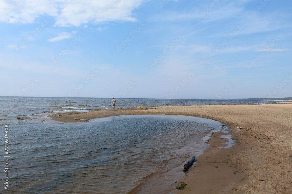 Man in summer standing on a tiny peninsula on the Baltic Sea in Saulkrasti, Latvia