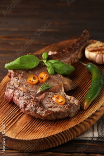 Delicious fried beef meat with garlic and chili pepper on wooden table