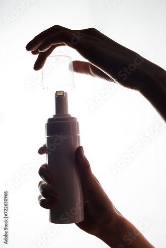 Close-up of a white mockup of a moisturizer tube with a dispenser in a woman hand on a white background.