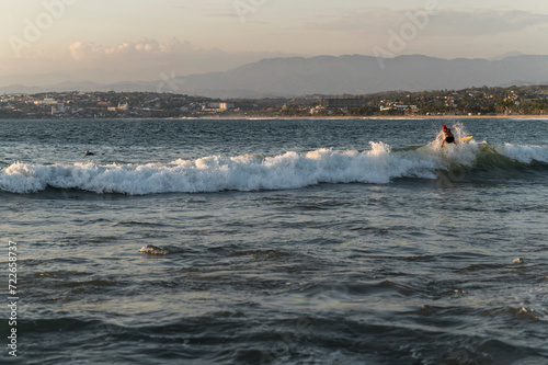 Skilled redhead woman surfer riding waves at golden hour in Pacific Coast of Oaxaca, Mexico photo