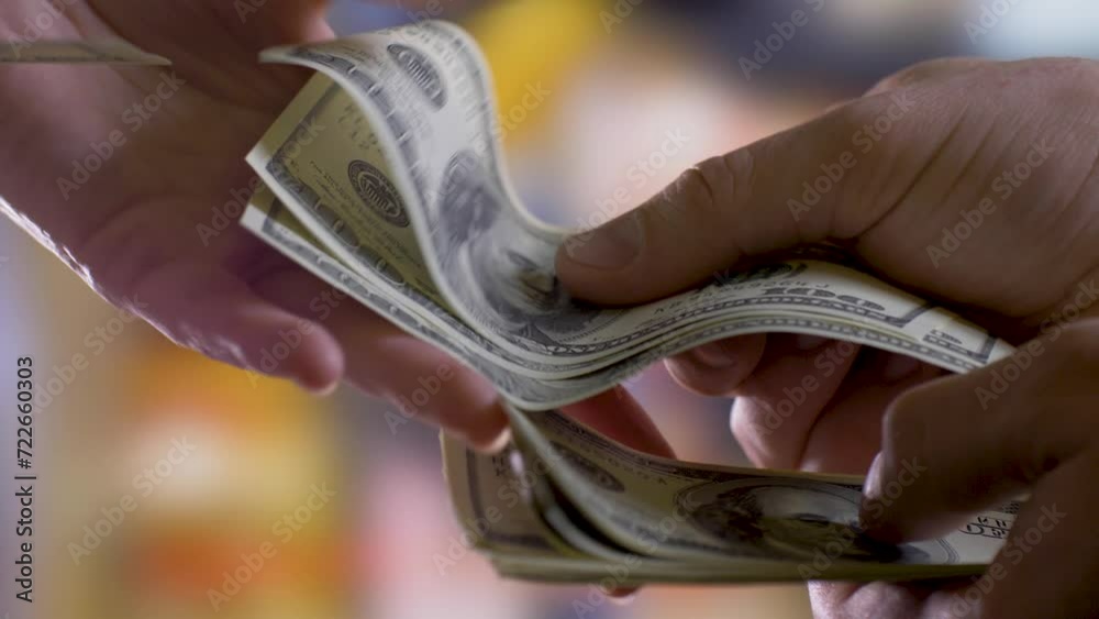 Person's hands count money and gradually hand them all to another person's hands reluctantly. Blurred people background. Loan, credit concept