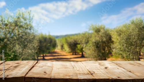 Old wooden table for product display with natural green olive field and green olives, beautiful sunny day of summer