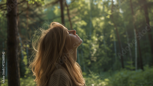森の中で頭を上にして目を閉じて深呼吸している女性の横顔、コピースペース有 photo