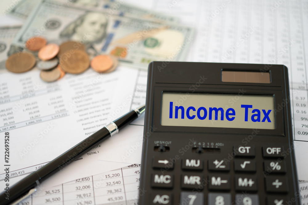 Income Tax concept. income tax word on calculator screen with money and tax report for tax pay on desk. Income Tax concept. income tax word on calculator screen with money and tax report for tax pay on desk.
