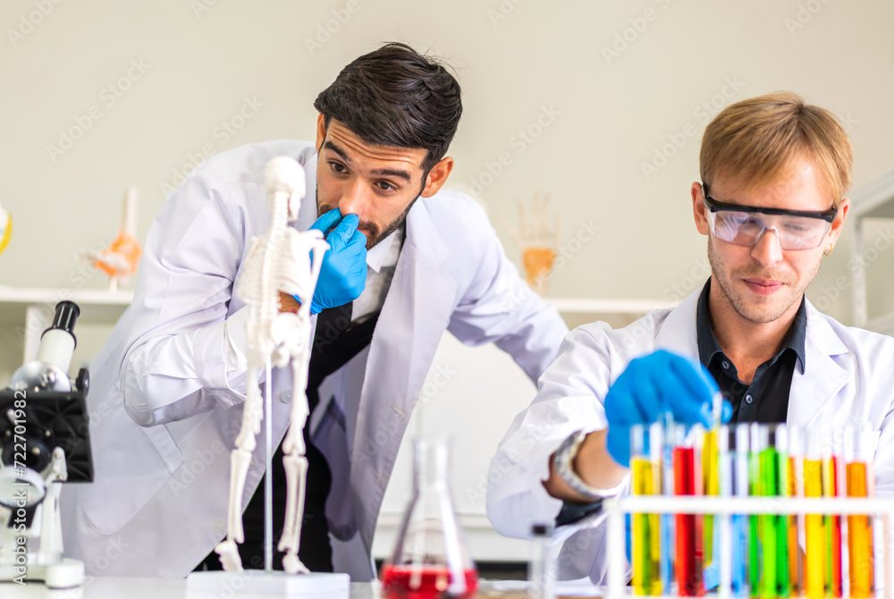 Professional two scientist man research and working doing a chemical experiment while making analyzing and mixing liquid in test tube.Young science man dropping sample chemical on glass at laboratory Professional two scientist man research and working doing a chemical experiment while making analyzing and mixing liquid in test tube.Young science man dropping sample chemical on glass at laboratory