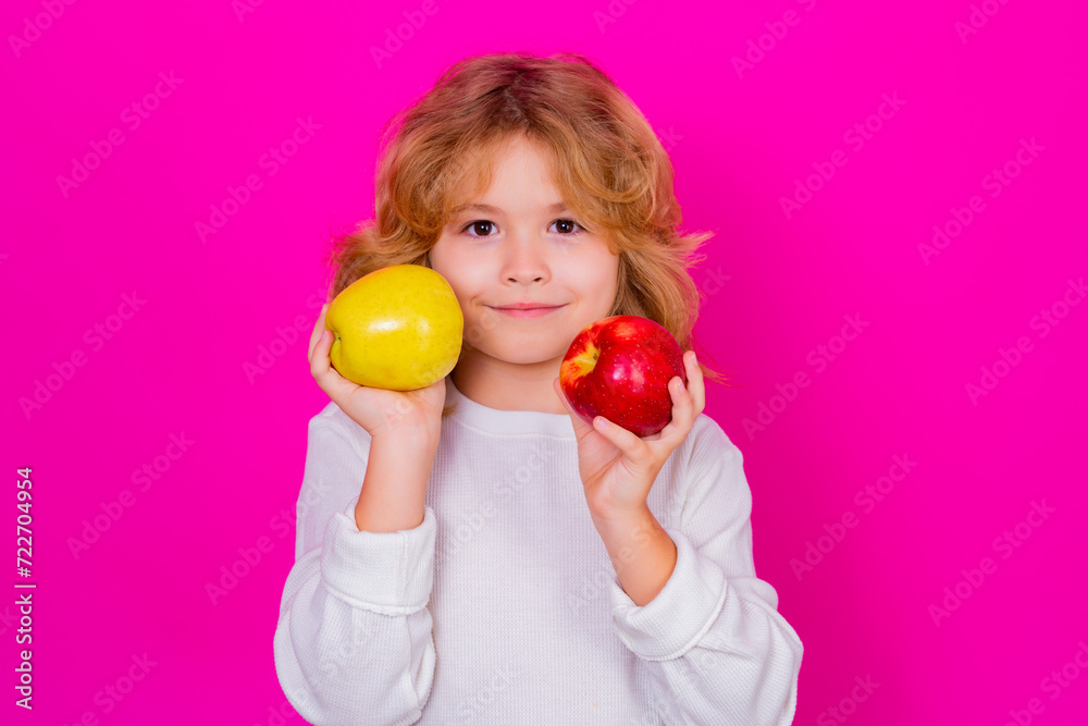 Kids face with fruits. Kid with apple in studio. Studio portrait of cute child hold apple isolated on pink background. Kids face with fruits. Kid with apple in studio. Studio portrait of cute child hold apple isolated on pink background.