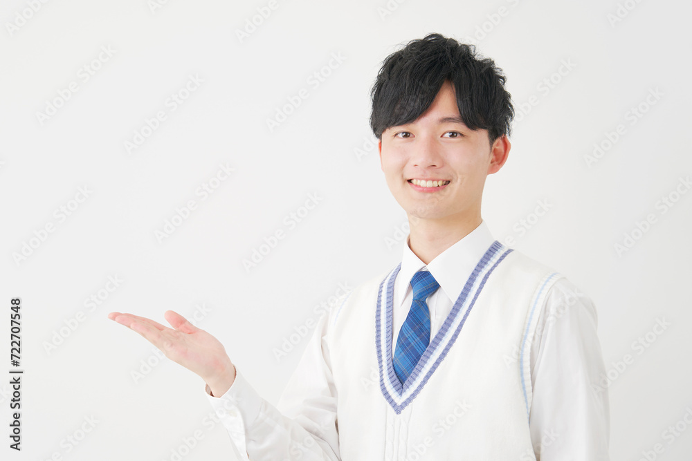 手の平で左側を指す男子高校生　白背景