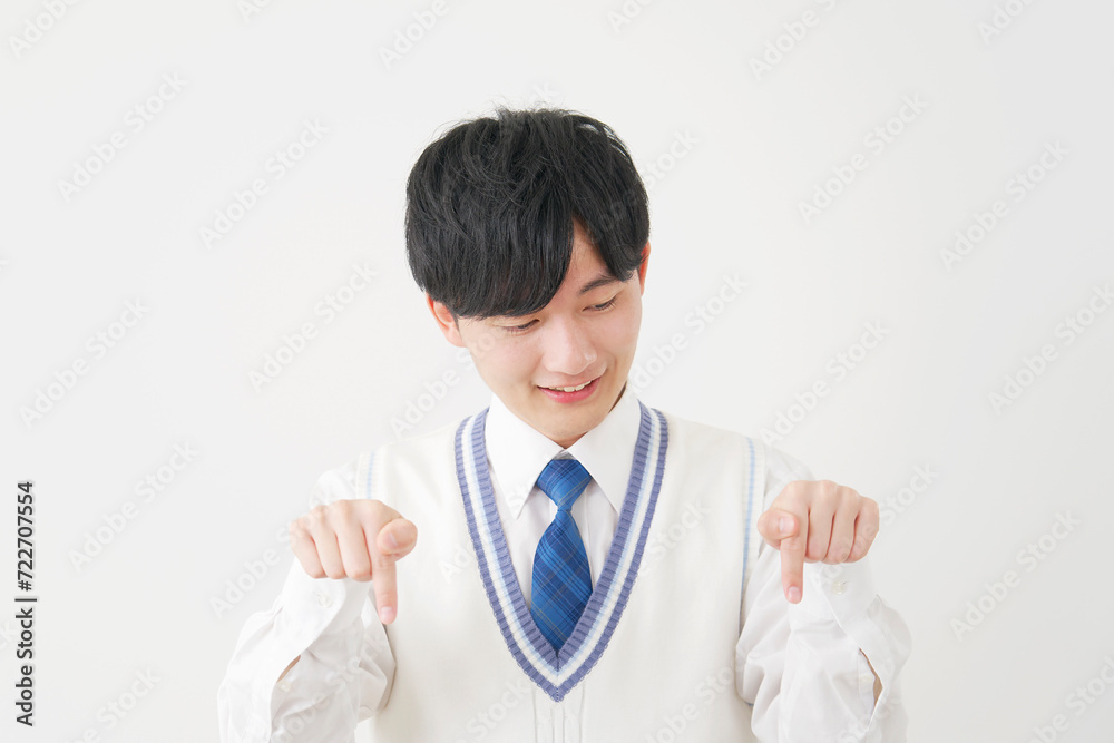 下を指差す男子高校生　白背景