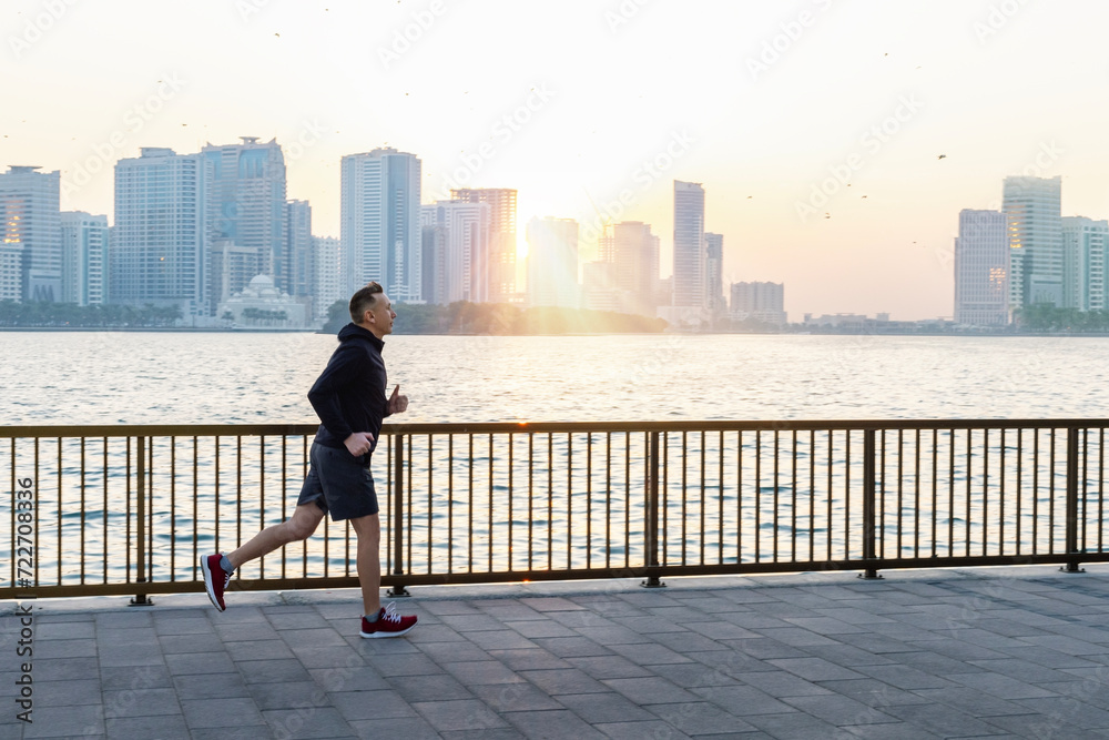 Morning run, a man runs along the waterfront with a beautiful view of Shurjah, UAE. Morning run, a man runs along the waterfront with a beautiful view of Shurjah, UAE.