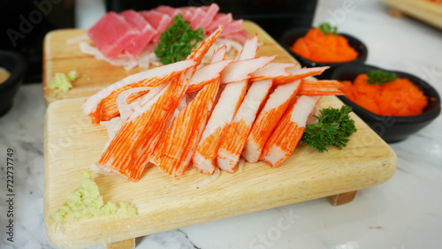 Sliced Imitation crab stick with wasabi serve on wooden dish. Japanese food crab sticks or surimi and wasabi prepared for eating on table, traditional Japanese food.