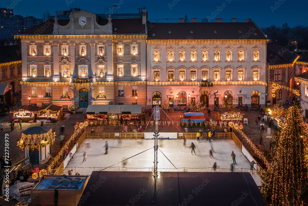 Budapest, Hungary - Aerial view of the Christmas market and ice rink on Szentlelek square, Obuda at dusk. Decorative illuminated shops, festive decoration and Christmas signs on the streets of Buda