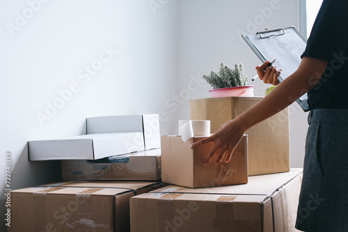 Woman checking and packing the carton box prepare to move to new house relocation shipping  photo