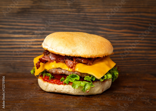 Burger, sandwich, hamburger with meat cutlet, bacon, tomato and cheese on a wooden background