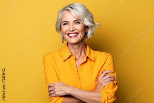 Portrait of a happy mature woman in yellow shirt over yellow background