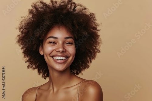 Happy African girl showcasing skin care results, beige studio