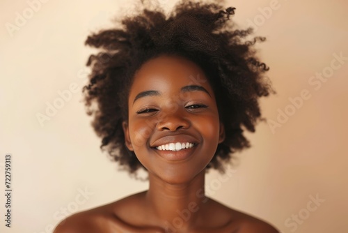 Joyful young African woman with flawless skin, beige backdrop