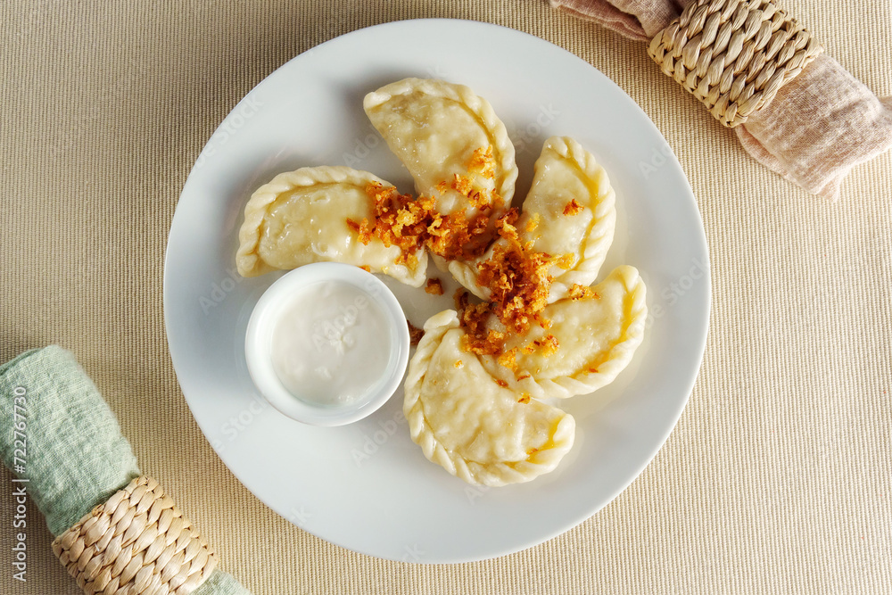 White plate showcases an array of delectable dumplings, perfectly paired with a luscious bowl of flavorful dip.